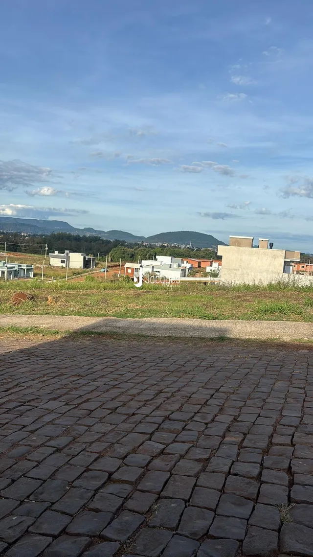 Vista externa de edificações e terreno com paisagem de fundo.