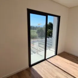 Vista externa através de portas de vidro com piso de madeira.
