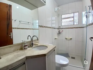 Foto interna de um banheiro com revestimento branco e bancada clara.