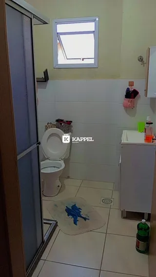 Foto de um banheiro com azulejos brancos e um vaso sanitário.