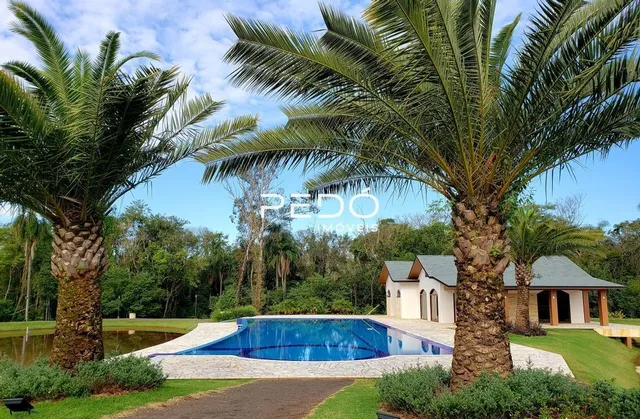 Vista externa de uma propriedade com piscina e jardim.