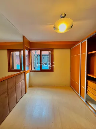 Interior de um ambiente com piso de madeira e armários embutidos.
