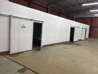 Fachada externa de um galpão industrial com portas de correr brancas.