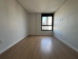 Foto de um cômodo com piso de madeira e uma grande janela mostrando vista urbana.