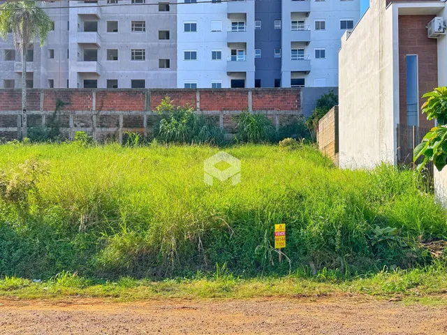 Vista externa de uma propriedade com gramado alto e muro de tijolos.