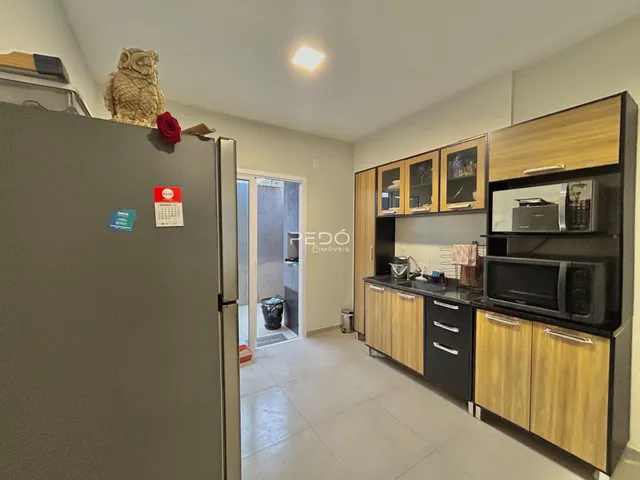 Interior de uma cozinha moderna com armários de madeira e eletrodomésticos.
