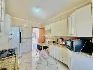Cozinha com armários brancos e piso de cerâmica clara.