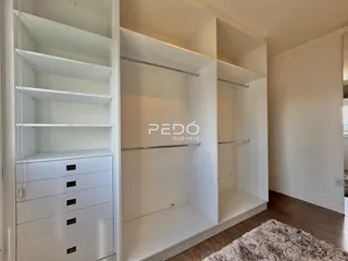 Vista de um ambiente interno com estantes brancas e armários em uma residência.