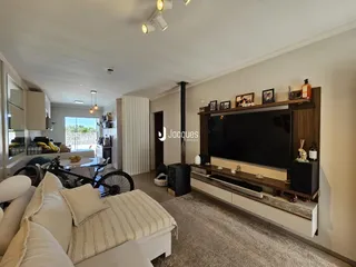 Sala de estar com sofá e televisão em um ambiente claro.