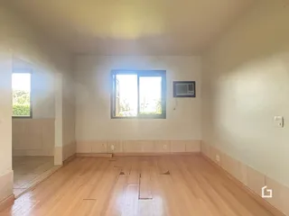 Sala de estar com piso de madeira e janela iluminada.