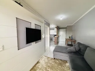 Sala de estar com sofá cinza e parede de painel branco.