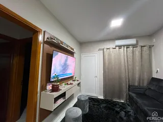 Sala de estar com televisão montada na parede e cortinas claras.
