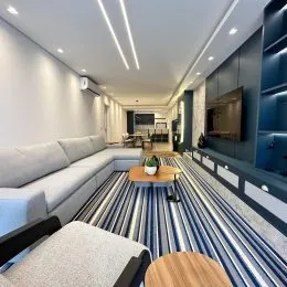 Sala de estar com sofá e iluminação moderna em um apartamento.