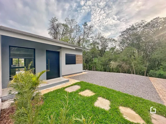 Fachada de uma casa moderna em Lajeado, Brasil com jardim e entrada de cascalho.