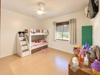 Quarto com cama de beliche e piso de madeira.