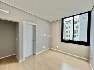 Ambiente interno de uma sala com piso de madeira e janela em um imóvel.