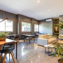 Foto de um ambiente interno com mesas e cadeiras em um espaço aberto.