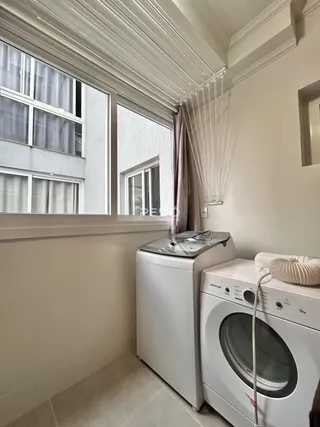 Uma foto de um ambiente interno mostrando máquinas de lavar roupa e janelas.