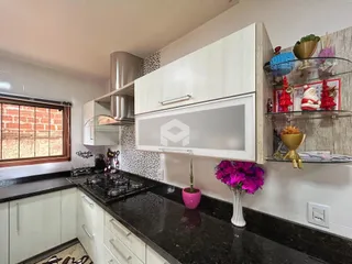 Uma cozinha moderna com armários brancos e bancadas escuras.