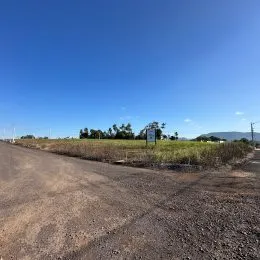 Vista de uma estrada de terra em uma área aberta sob um céu azul.
