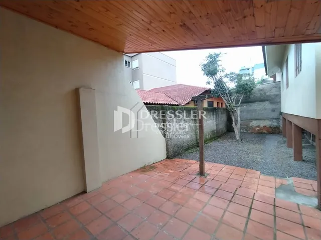 Uma área interna com piso de tijolos vermelhos e teto de madeira.
