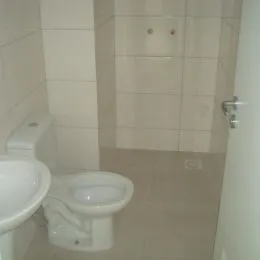 Foto interna de um banheiro com revestimento de azulejos brancos.