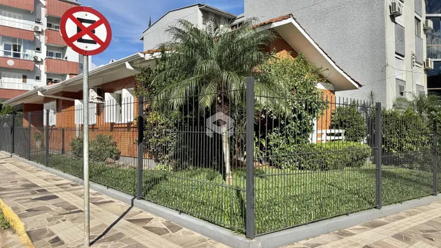 Vista da fachada de uma residência com cerca e vegetação no Brasil.