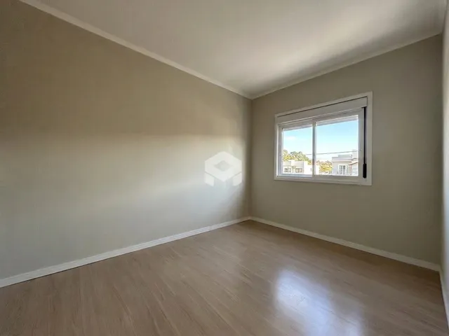 Vista interna de um cômodo com piso de madeira e janela.