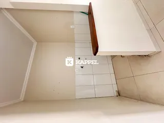 Vista interna de um cômodo com paredes brancas e revestimento de azulejos brancos.