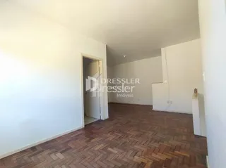 Interior de um ambiente com piso de madeira e paredes brancas.