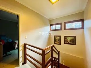Corredor com grade de madeira e quadros nas paredes de uma residência.