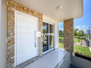 A foto mostra a varanda com piso claro e vista para o jardim.