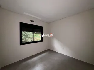 Foto de um corredor interno com paredes brancas e piso cinza.