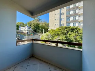 Vista da varanda com árvores e prédio ao fundo.