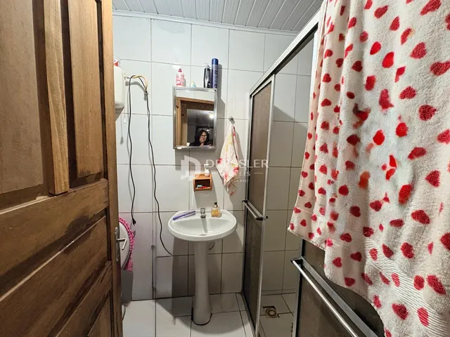 Foto de um banheiro com revestimento cerâmico branco.