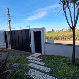 Vista externa da propriedade com muro branco e gramado.