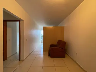 Hall de entrada com piso de cerâmica clara e parede branca.