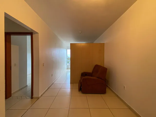 Hall de entrada com piso de cerâmica clara e parede branca.