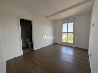 A sala de estar apresenta piso de madeira clara e paredes brancas.