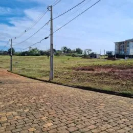 Vista externa de um terreno aberto com grama e caminho de tijolos.