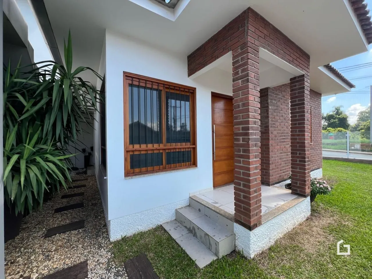 Fachada de uma casa em Lajeado, Brasil com pilar de tijolos e jardim gramado.