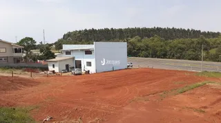 Vista externa de terra vermelha com vegetação ao fundo.