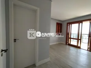Hall de entrada com porta branca e piso de madeira clara.