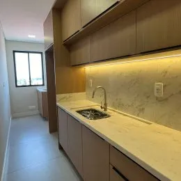 Cozinha com armários superiores de madeira e bancada clara.
