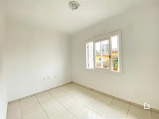 Ambiente interno de uma sala com piso de cerâmica e paredes brancas.