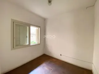 Interior de um cômodo com parede branca e piso de madeira.