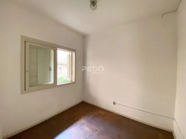 Interior de um cômodo com parede branca e piso de madeira.