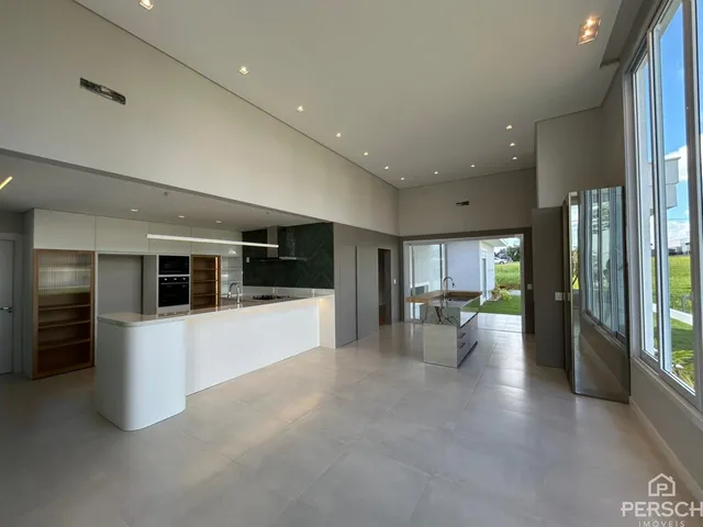 Vista de uma cozinha moderna com ilha branca e piso claro em um imóvel em Lajeado.