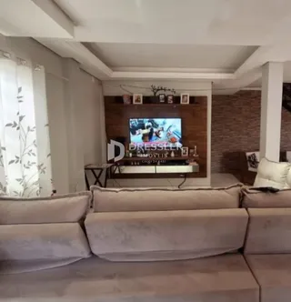 Sala de estar com sofá e televisão em ambiente interno.