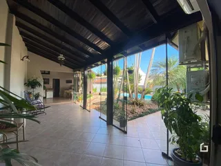 Vista de uma área externa com piscina e jardim através de grandes portas de vidro.